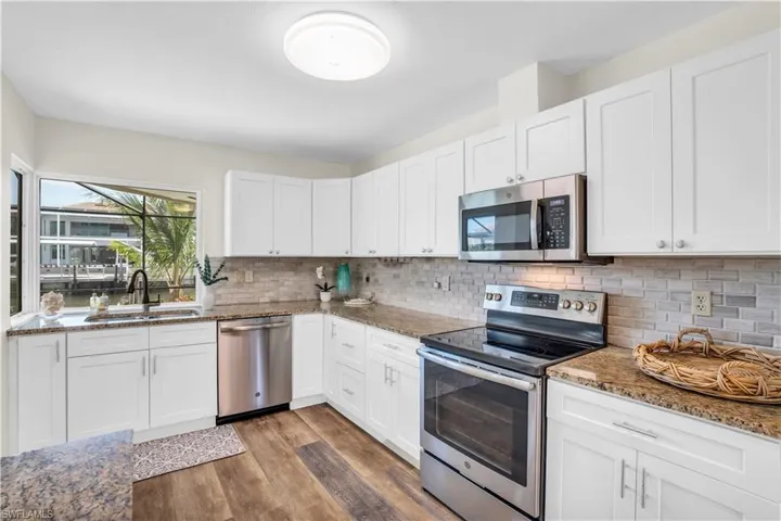 Kitchen with appliances with stainless steel finishes, white cabinetry, sink, and backsplash