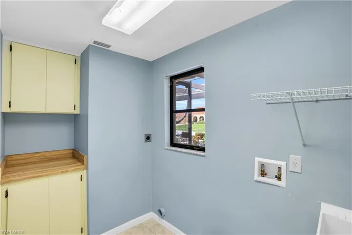 Laundry area with hookup for a washing machine, cabinets, light tile floors, and hookup for an electric dryer