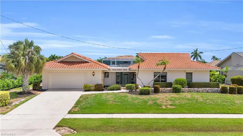 Mediterranean / spanish-style house with a garage and a front lawn