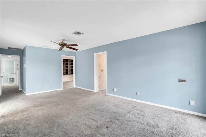 Unfurnished bedroom featuring a spacious closet, a closet, carpet floors, and ceiling fan
