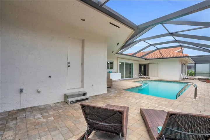 View of pool featuring glass enclosure and a patio area