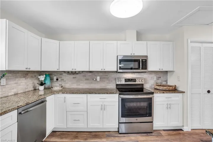Kitchen featuring white cabinetry, dark hardwood / wood-style floors, tasteful backsplash, and stainless steel appliances