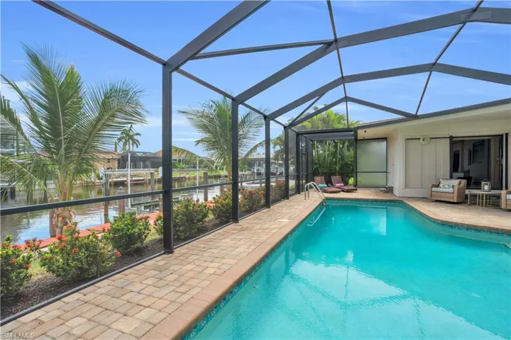 View of pool with a patio, glass enclosure, and a water view