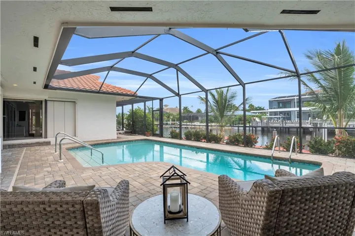 View of swimming pool with a water view, glass enclosure, and a patio area