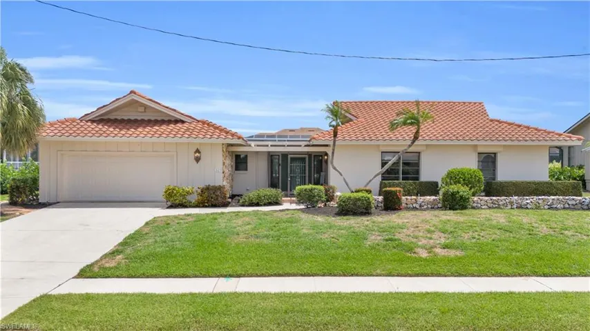 View of front of home featuring a garage, a front yard, and solar panels