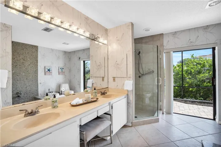 Bathroom featuring walk in shower, tile flooring, a textured ceiling, double sink, and large vanity