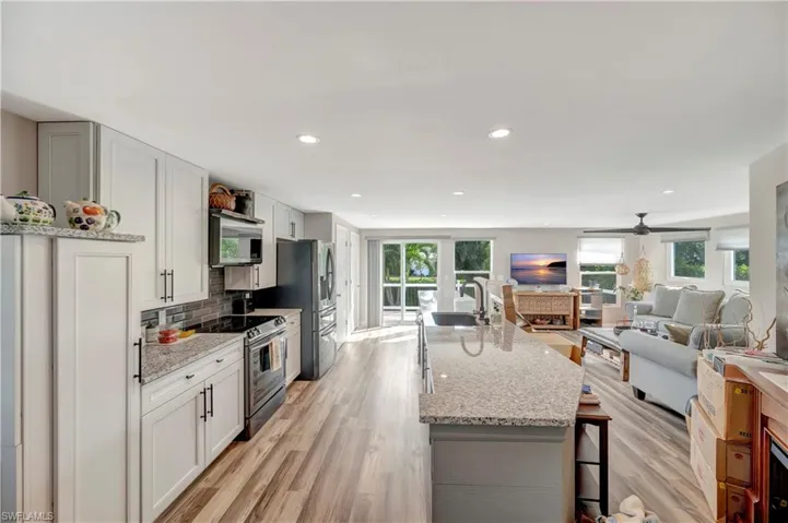 Kitchen featuring white cabinets, ceiling fan, light stone countertops, tasteful backsplash, and stainless steel appliances