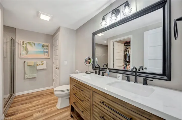 Bathroom with wood-type flooring, vanity, toilet, and walk in shower