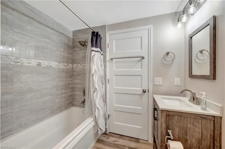 Bathroom with hardwood / wood-style flooring, vanity, and shower / tub combo with curtain