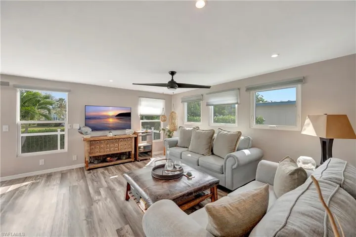 Living room with ceiling fan, light hardwood / wood-style flooring, and a healthy amount of sunlight