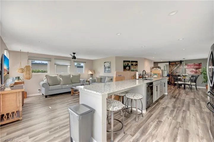 Kitchen featuring light stone countertops, light hardwood / wood-style flooring, a breakfast bar area, and an island with sink