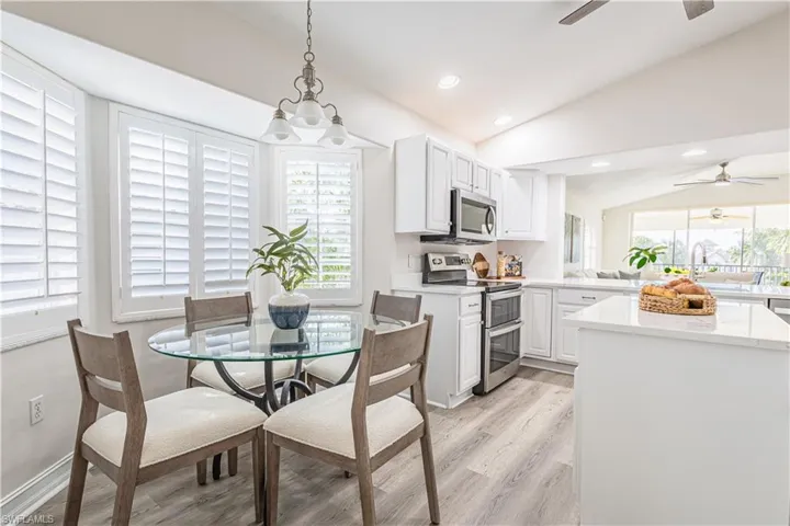 Dining space featuring lofted ceiling, ceiling fan, light wood finished floors, and hanging lights