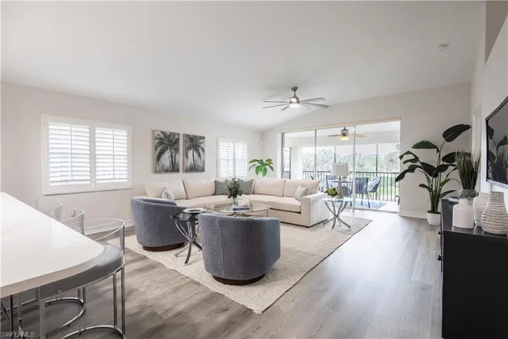 Living room with vaulted ceiling, healthy amount of natural light, wood finished floors, and a ceiling fan