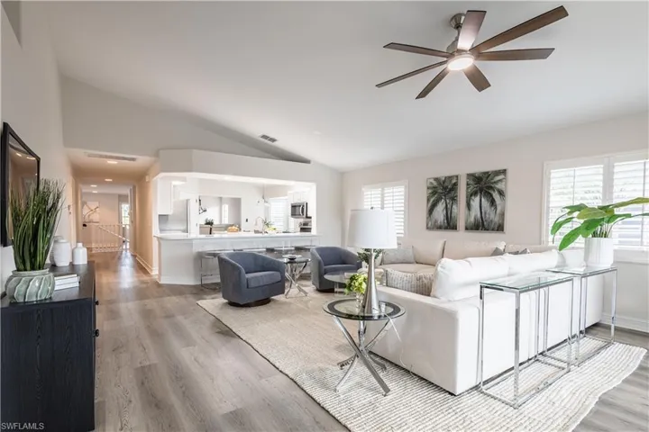 Living area with lofted ceiling, ceiling fan, and light wood-style flooring