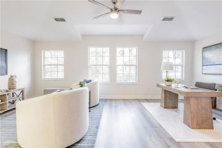 Home office with ceiling fan, light wood finished floors, and healthy amount of natural light