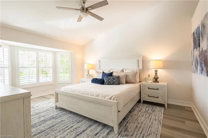 Bedroom with wood finished floors, a ceiling fan, and vaulted ceiling