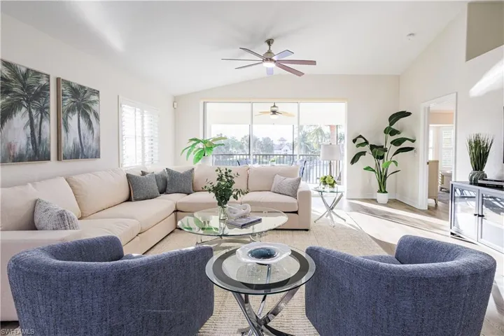 Living room with lofted ceiling, light wood-style floors, healthy amount of natural light, and a ceiling fan