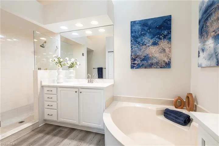 Full bathroom featuring vanity, a garden tub, walk in shower, and light wood-style floors