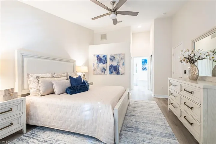 Bedroom with a ceiling fan, light wood-style floors, and ensuite bath