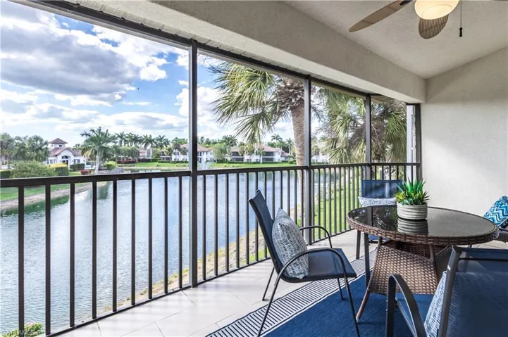 Sunroom / solarium featuring a balcony, ceiling fan, a water view, lofted ceiling, and a residential view