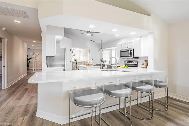 Kitchen featuring white cabinets, a peninsula, recessed lighting, stainless steel appliances, and light stone counters