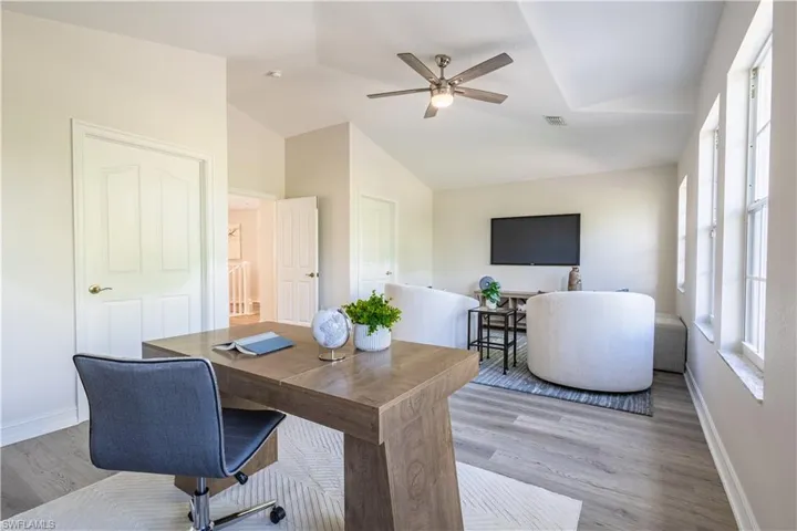 Office space featuring light wood-style flooring, ceiling fan, and lofted ceiling