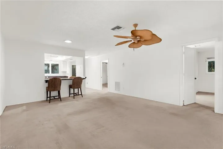 Living area with light colored carpet, a ceiling fan, and a textured ceiling