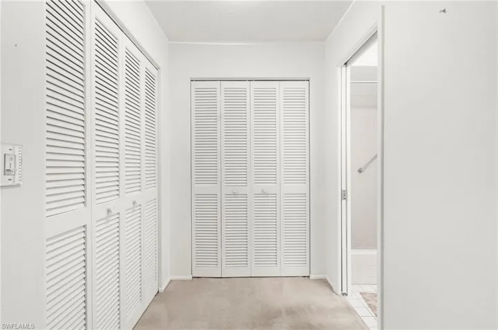 Corridor with light carpet and a textured ceiling