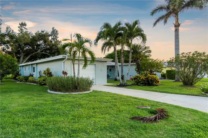 View of front of property featuring driveway, stucco siding, and a front yard