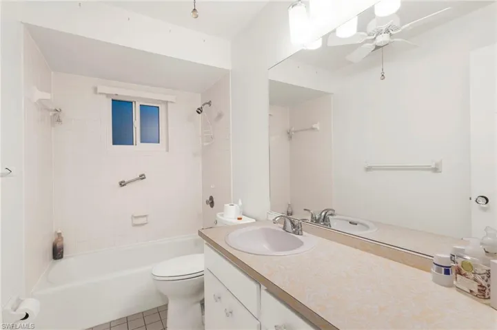 Bathroom with bathtub / shower combination, vanity, light tile patterned flooring, and a ceiling fan