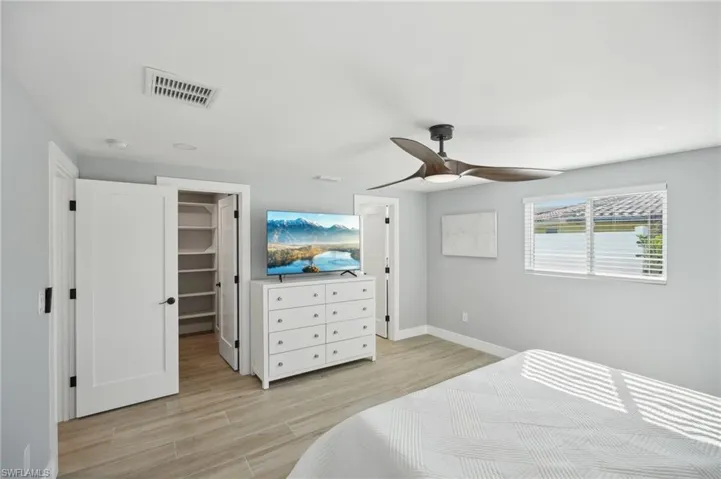 Bedroom with a spacious closet, light wood-style floors, and ceiling fan