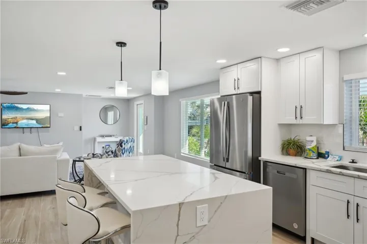 Kitchen featuring appliances with stainless steel finishes, light wood finished floors, plenty of natural light, light stone counters, and recessed lighting