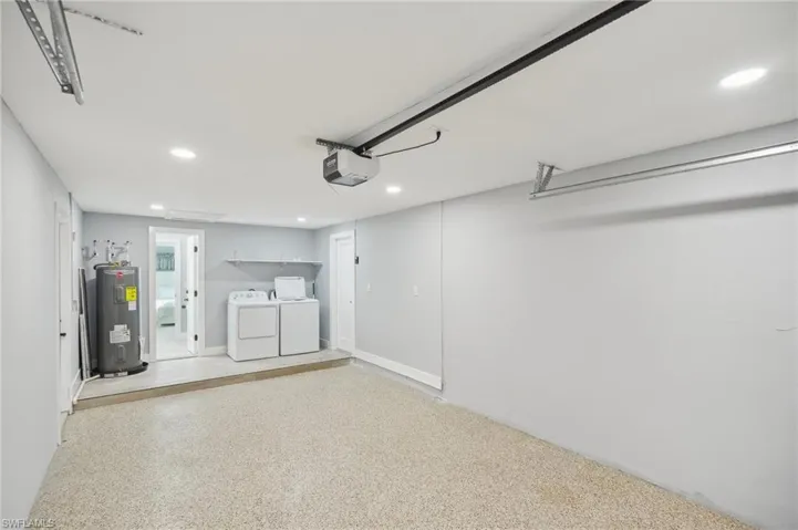 Garage with recessed lighting, washing machine and clothes dryer, electric water heater, and a garage door opener