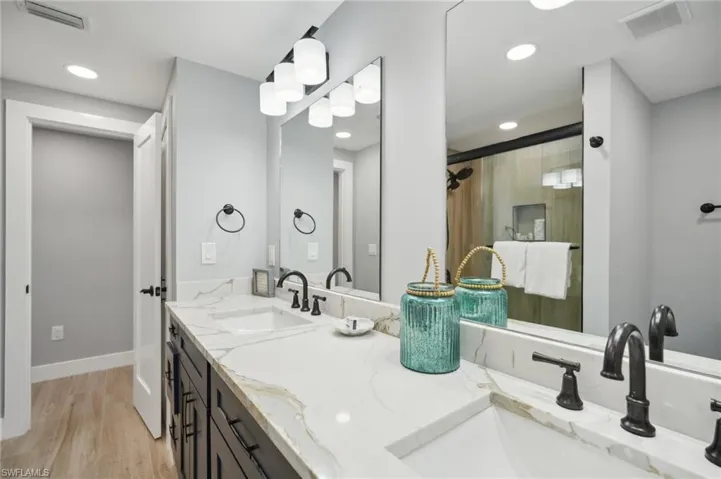 Full bathroom with light wood-style flooring, a shower stall, double vanity, and recessed lighting