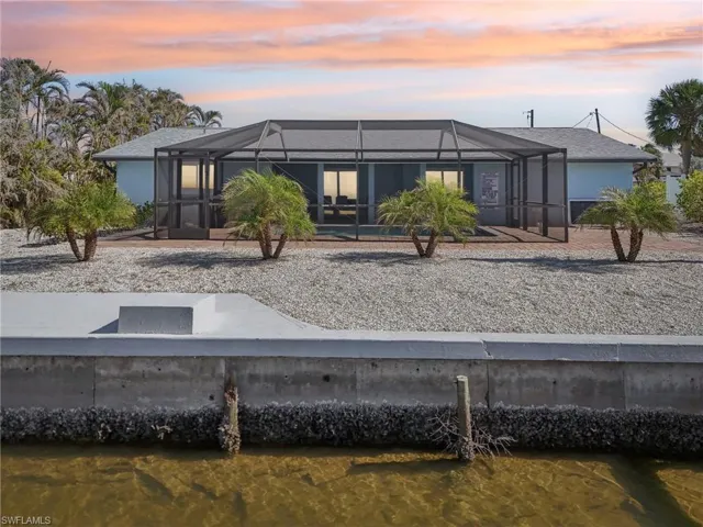 Back of house at dusk featuring a sunroom, a lanai, and stucco siding