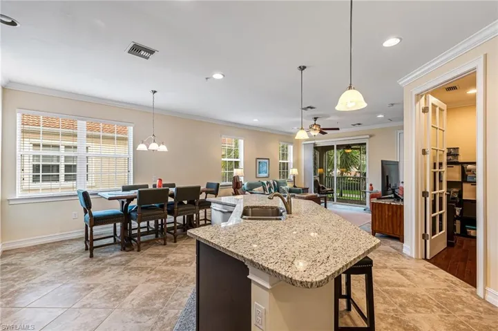 Kitchen featuring an island with sink, ceiling fan with notable chandelier, and decorative light fixtures