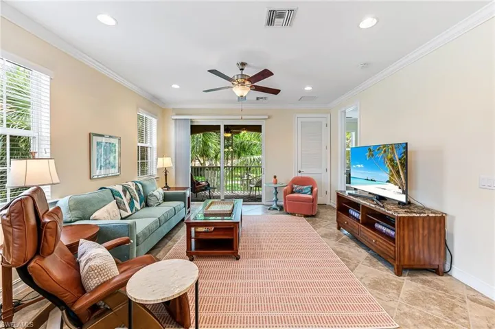 Living room with crown molding, ceiling fan, and light tile floors