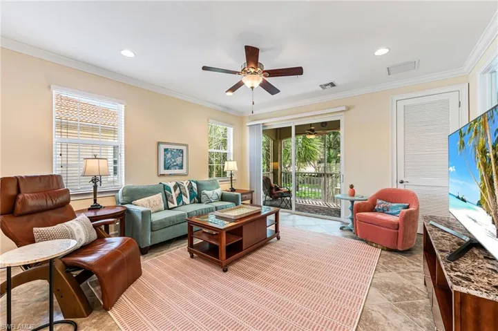 Tiled living room featuring ceiling fan and ornamental molding