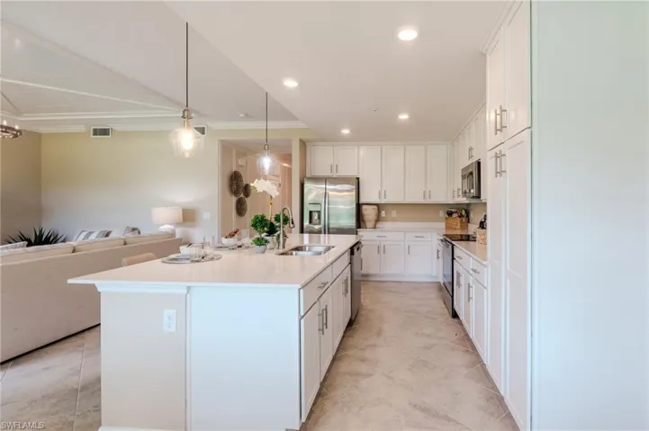 Kitchen featuring white shaker cabinetry, stainless steel appliances, a large center island with counter seating, pendant lighting, and recessed ceiling lights