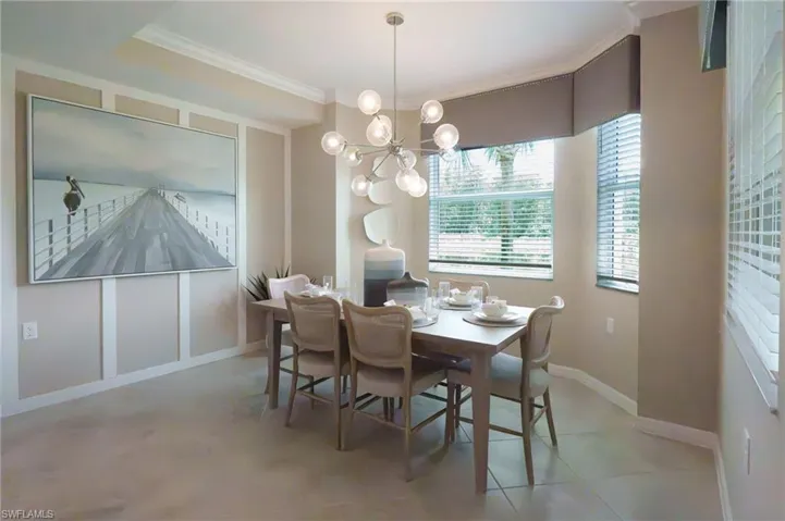 Dining area featuring a modern chandelier, bay window with blinds, panel molding, and tile flooring