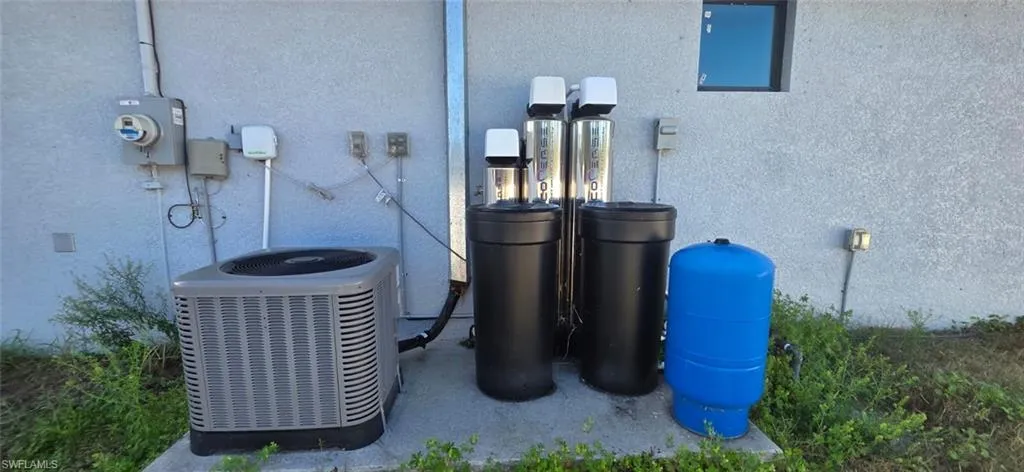 Exterior view of stucco siding, a water softener, and a water pressure tank