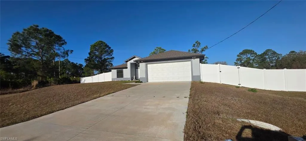 View of front facade with concrete driveway, stucco siding, a garage, and a gate