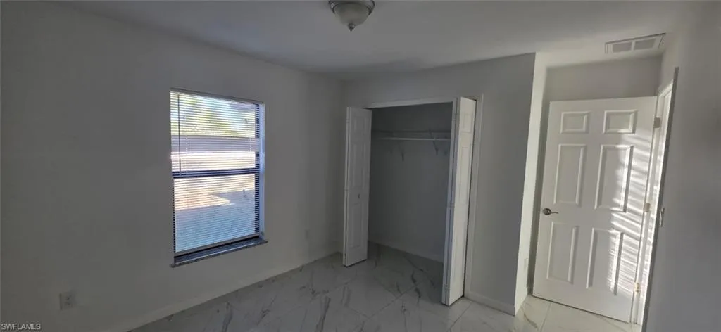 Unfurnished bedroom with light marble finish floors and a closet