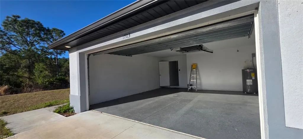 Garage with water heater and driveway