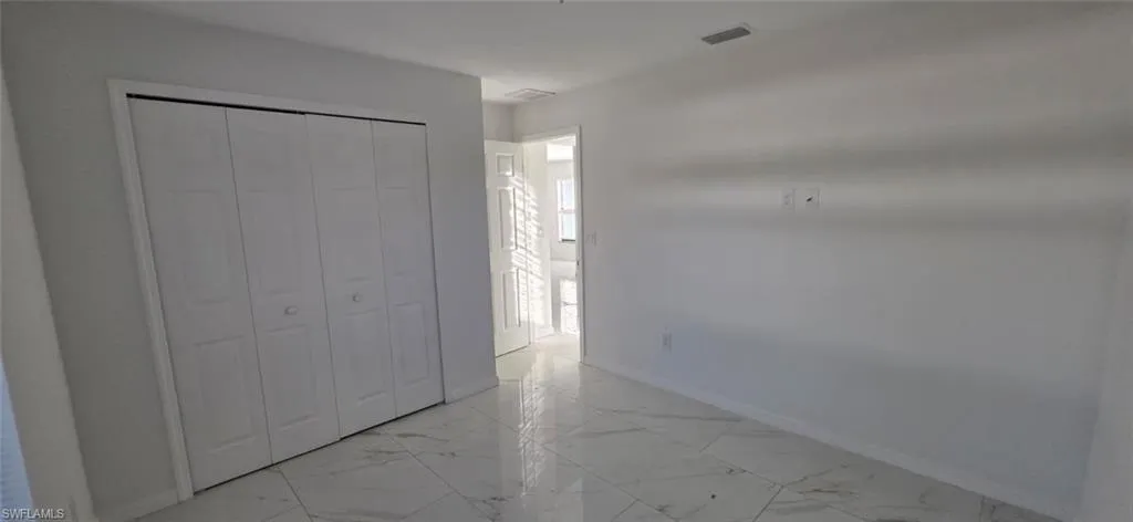 Unfurnished bedroom featuring light marble finish floors and a closet