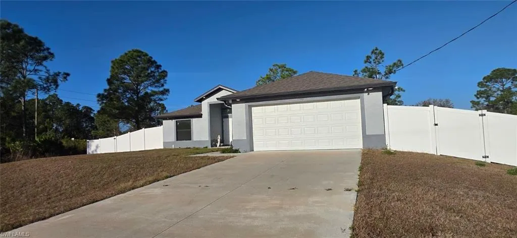 View of front of property featuring a gate, stucco siding, concrete driveway, a garage, and a shingled roof