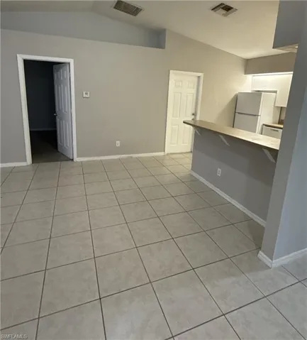 Unfurnished living room with light tile patterned floors and lofted ceiling