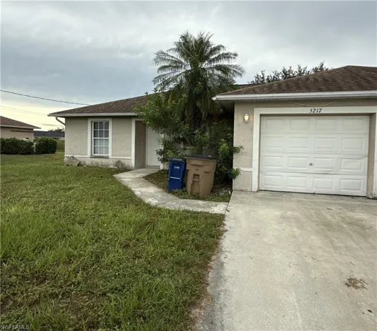Ranch-style house featuring stucco siding, a front yard, concrete driveway, and a garage