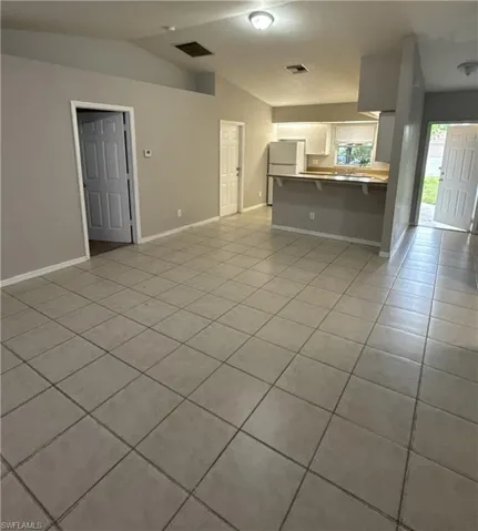 Living area featuring light tile patterned floors and vaulted ceiling