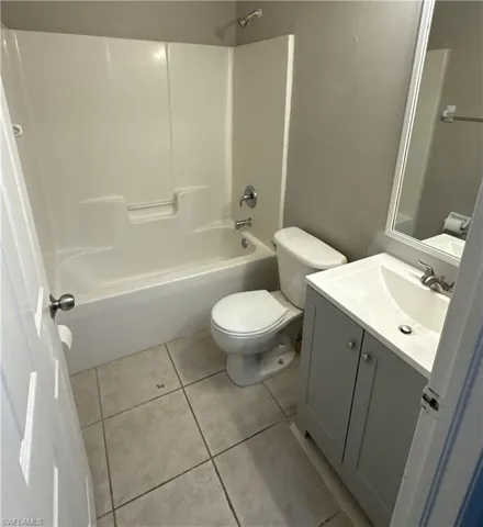Bathroom with vanity, shower / bath combination, and light tile patterned floors